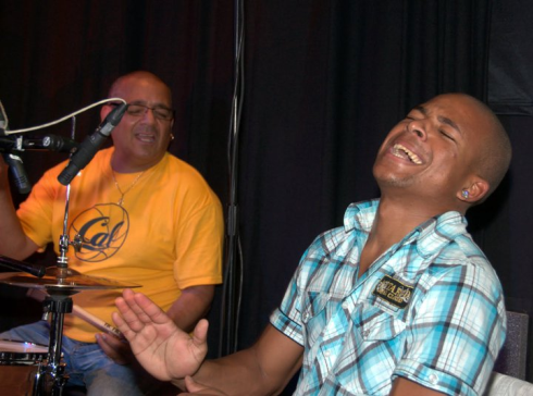 Yarien Oviedo playing percussion with his father Calixto